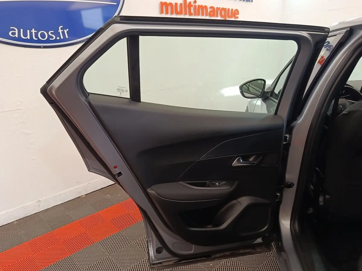 Vue intérieure de la porte arrière gauche gris clair d’un Peugeot E-2008 électrique 2023, avec garniture noire et poignée argentée.