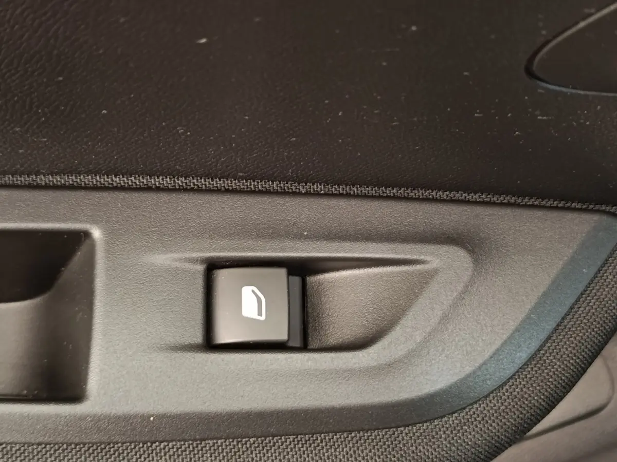 Bouton de commande de lève-vitre sur la portière intérieure côté conducteur du Peugeot E-2008 électrique gris clair 2023.