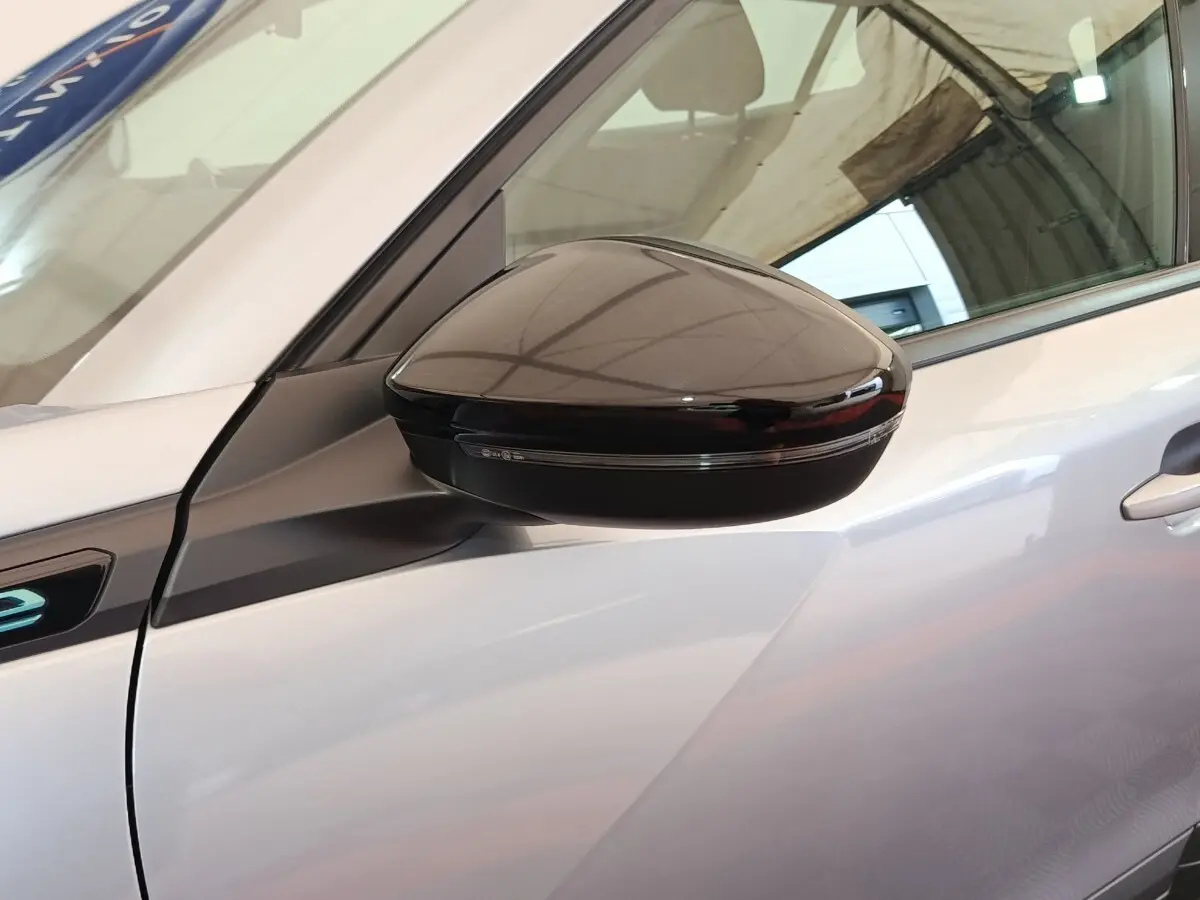 Gros plan sur le rétroviseur droit noir brillant du Peugeot E-2008 électrique gris clair, côté avant du véhicule.