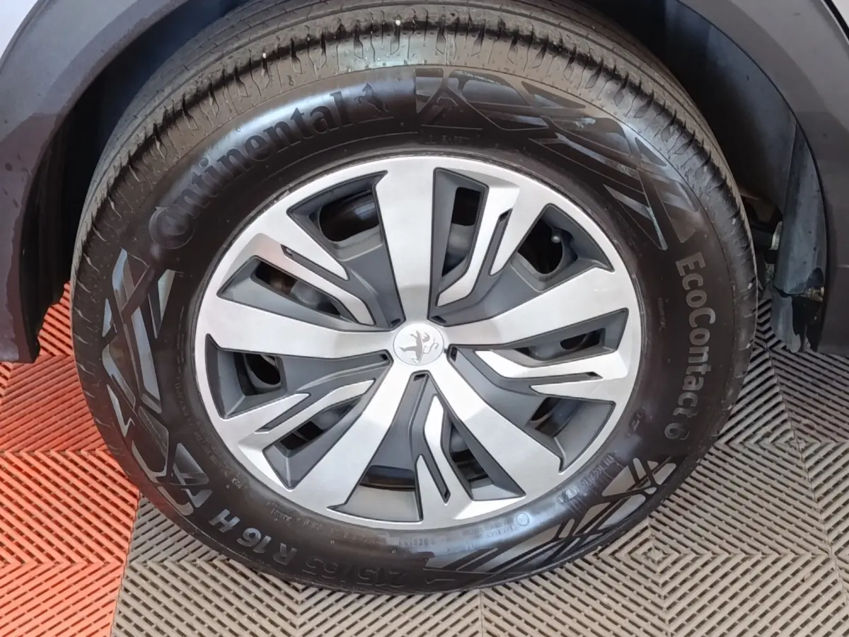 Gros plan sur la roue avant droite de la Peugeot E-2008 électrique gris clair avec jante alliage et pneu Continental.