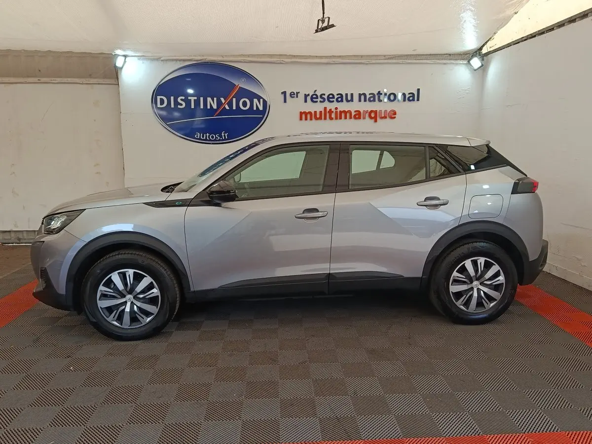 Profil côté gauche du Peugeot E-2008 électrique gris clair 2023, avec jantes alliage et toit noir contrastant.