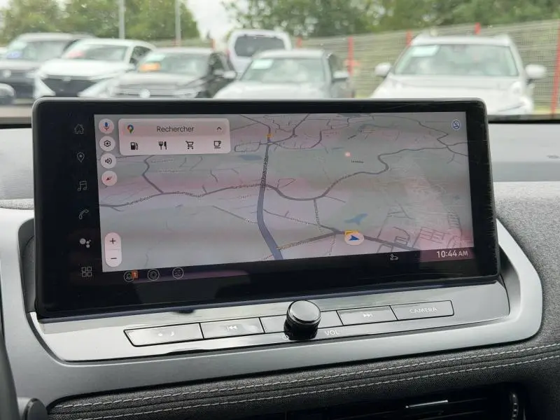 Écran tactile central du Nissan Qashqai 2025 affichant une carte GPS, avec commandes audio et bouton volume en dessous.
