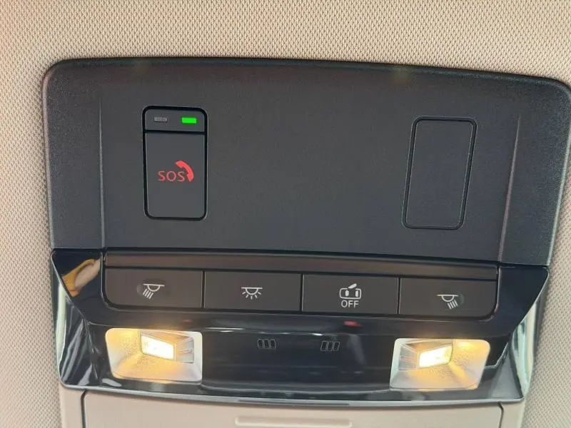 Vue en gros plan du plafonnier intérieur du Nissan Qashqai blanc nacré, avec éclairages de lecture allumés et bouton SOS visible.