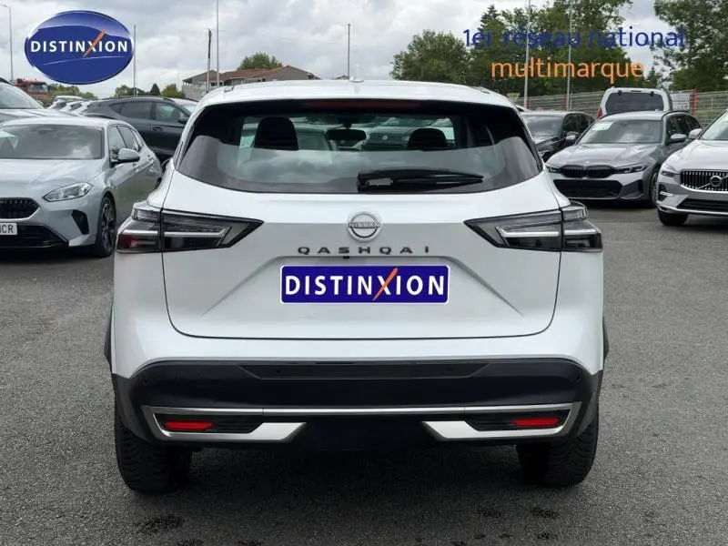 Vue arrière d'un Nissan Qashqai blanc nacré 2025 avec feux arrière LED et logo distinctif sur parking.