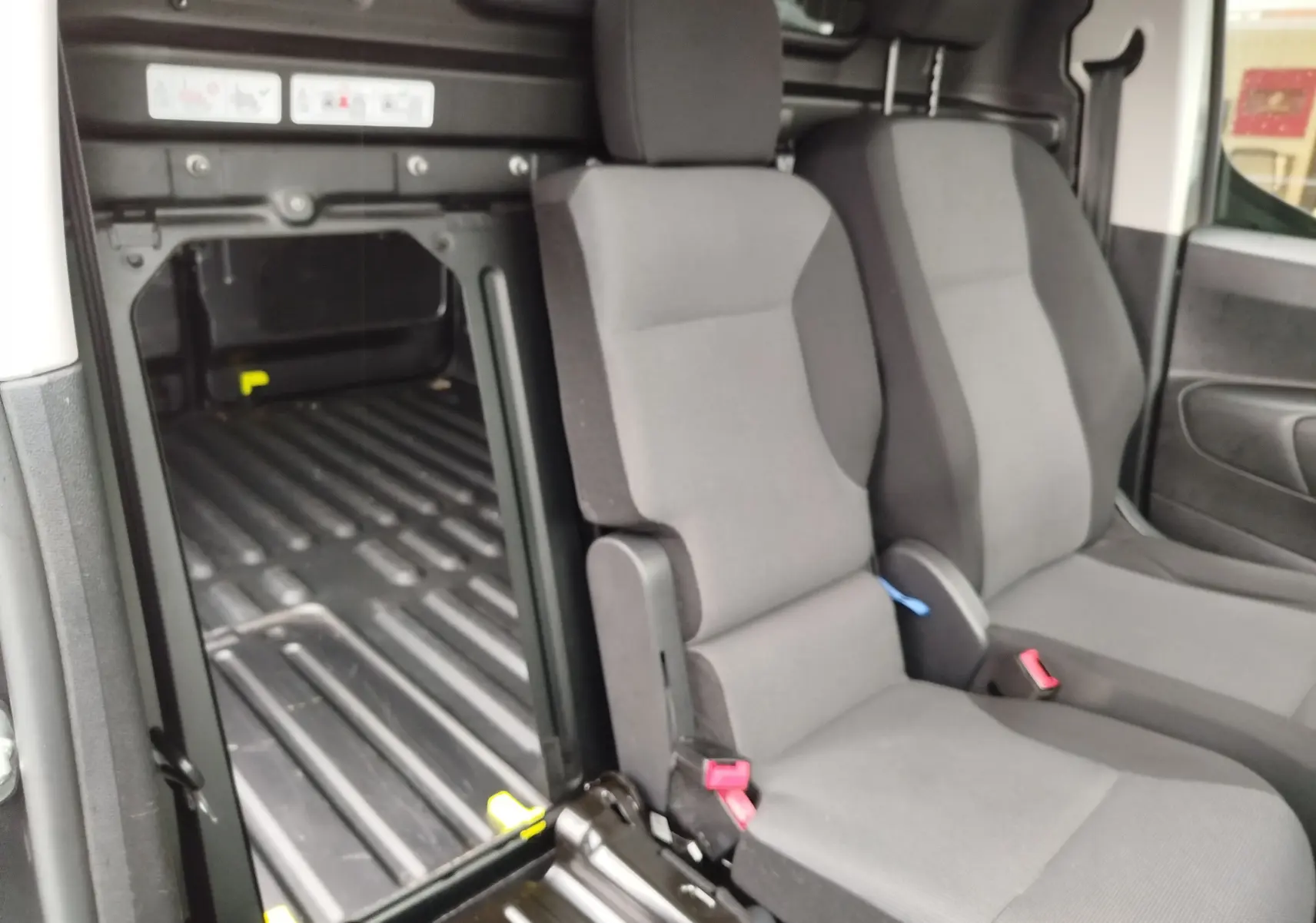 Vue intérieure côté droit du Peugeot Partner 2020, montrant les sièges avant gris et l’espace de chargement vide.