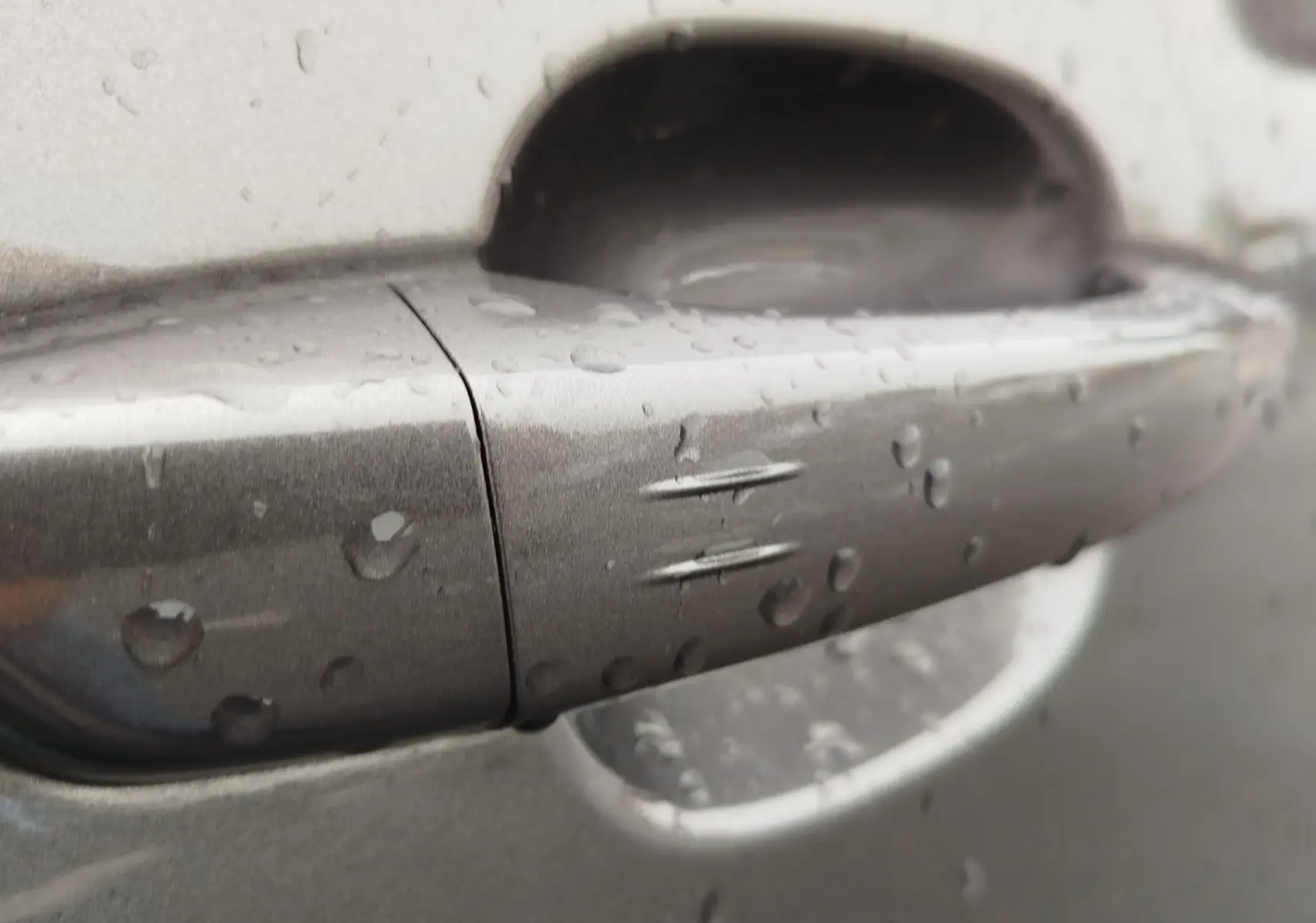 Poignée de porte gris foncé du Peugeot Partner 2020 avec gouttes d'eau, vue rapprochée sur le côté droit.