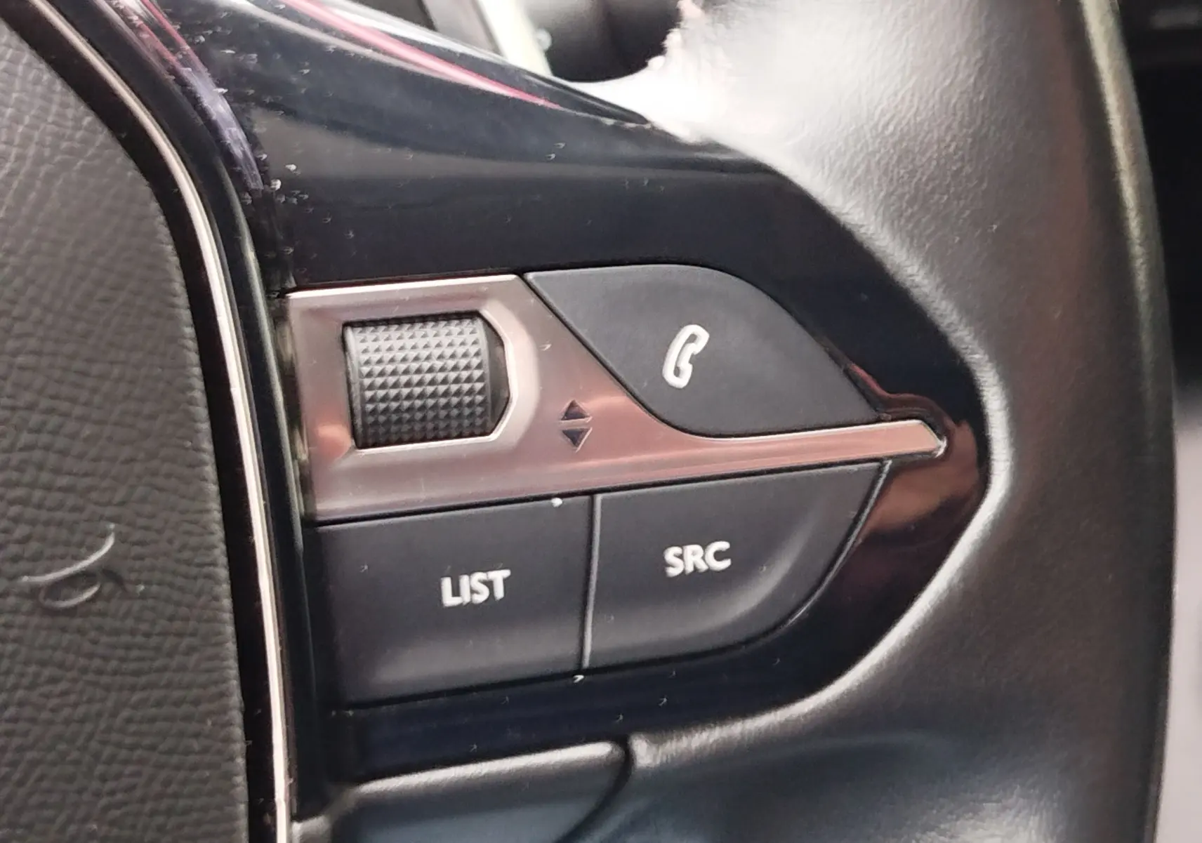Gros plan sur les commandes au volant côté gauche du Peugeot Partner 2020, boutons noirs avec fonction appel et liste.