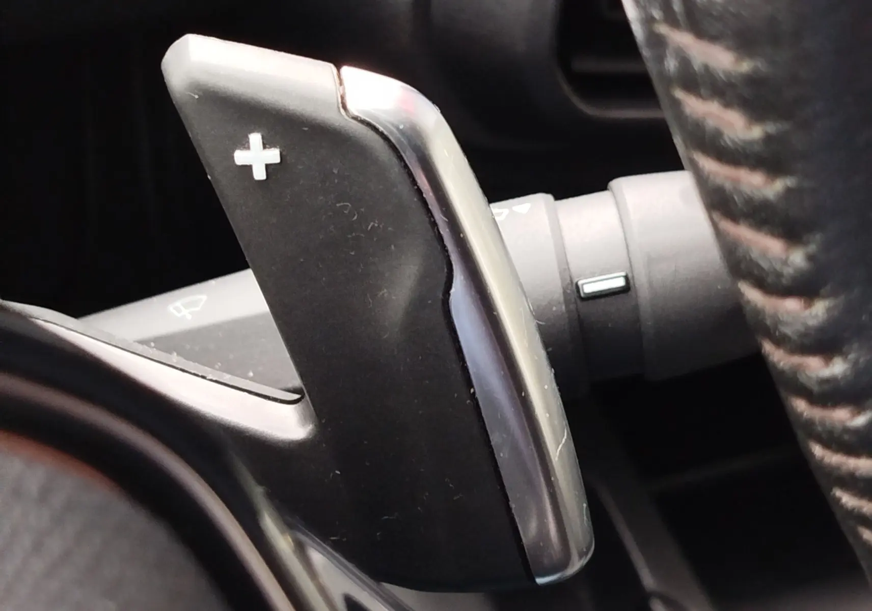 Gros plan sur la palette de passage de vitesse "+" en plastique noir et chrome, à droite du volant du Peugeot Partner gris foncé.
