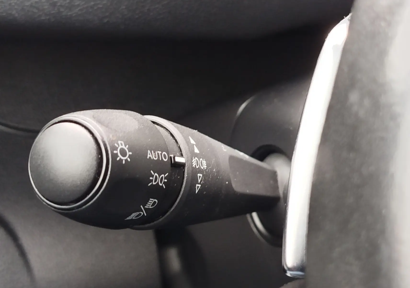 Gros plan sur la commande des phares à gauche du volant dans l’habitacle gris foncé du Peugeot Partner 2020.