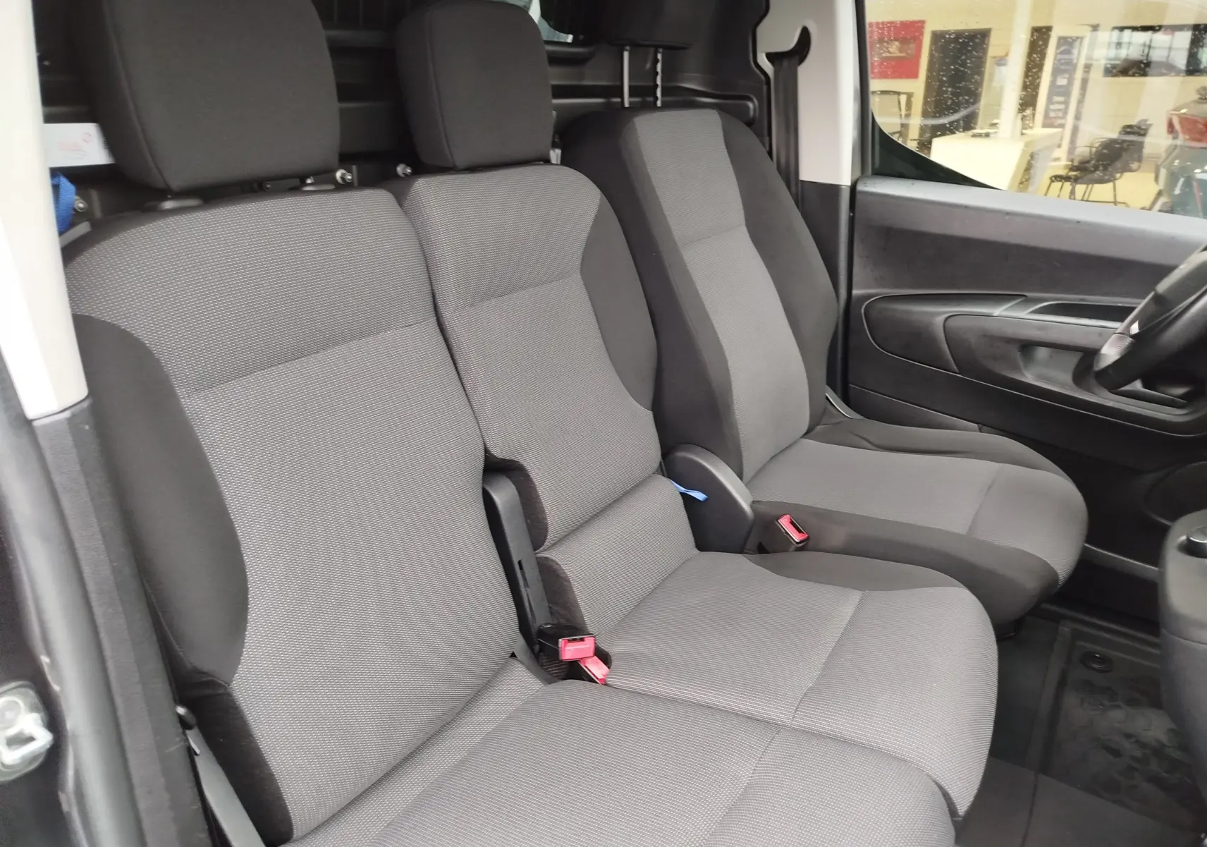 Vue intérieure côté droit montrant les sièges avant gris foncé du Peugeot Partner 2020 avec banquette passager triple.