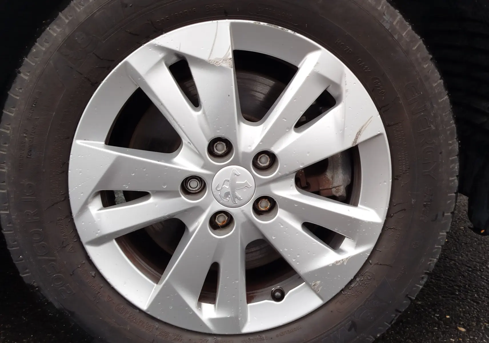 Gros plan sur la jante argentée d’un Peugeot Partner 2020, avec logo lion au centre et traces de boue sur le pneu noir.