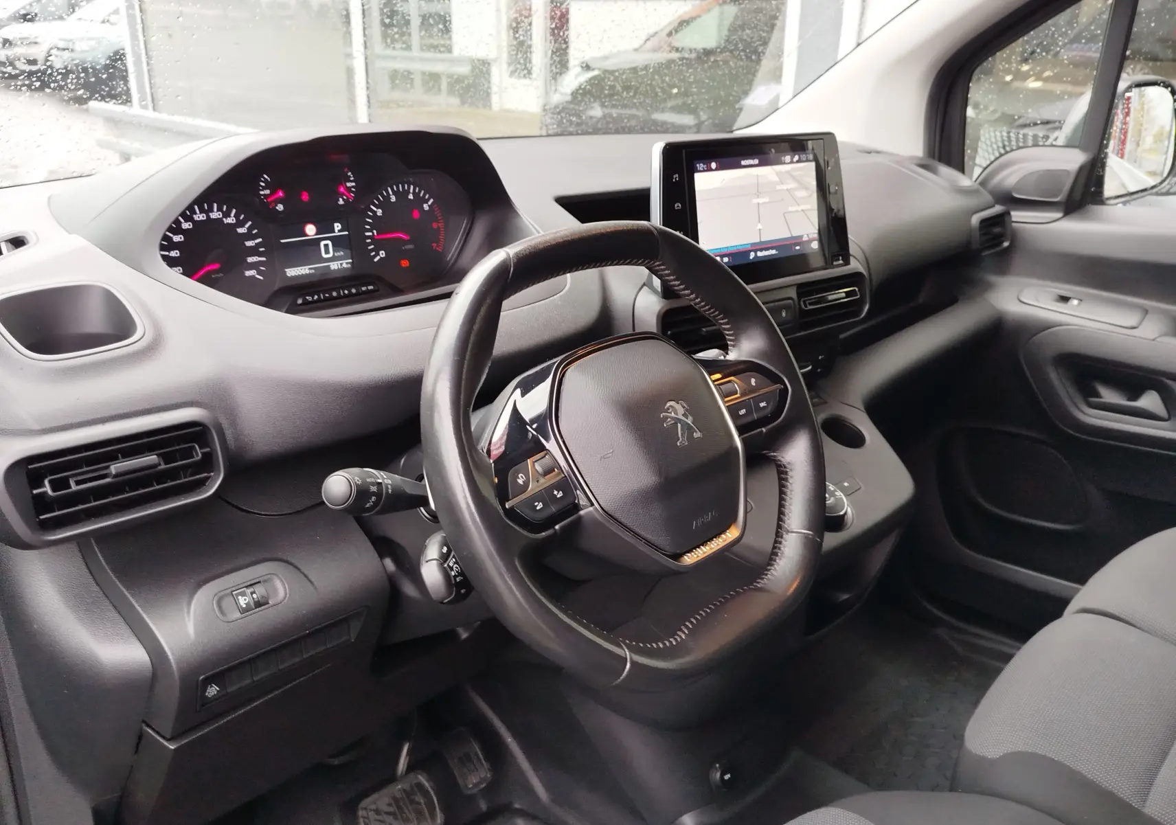 Vue intérieure côté conducteur du Peugeot Partner 2020, tableau de bord noir avec écran tactile et volant multifonction.