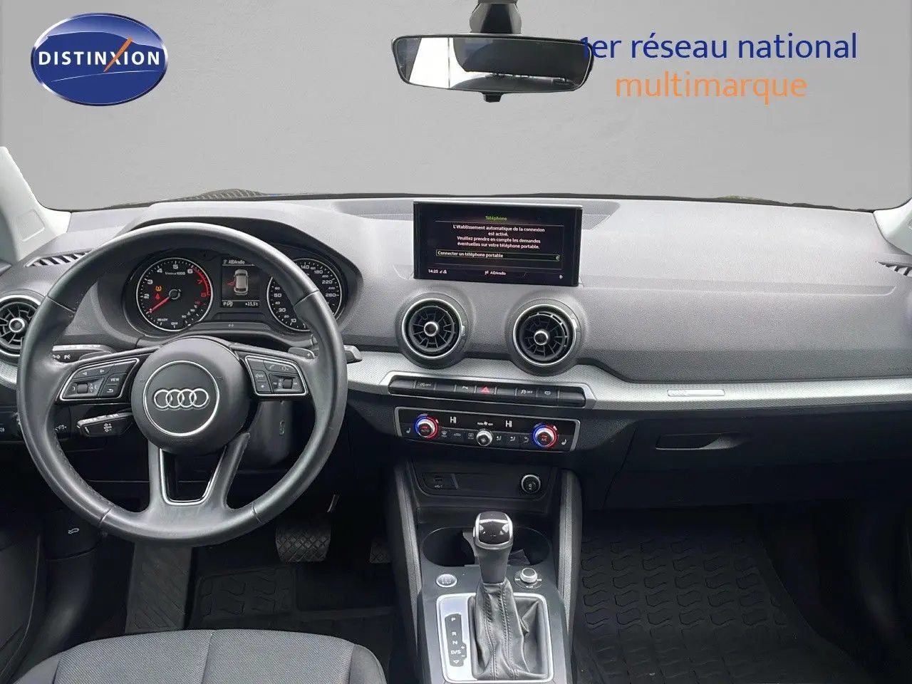 Vue intérieure avant de l'Audi Q2 35 TFSI S-Line 2023, tableau de bord gris avec volant multifonction et écran central.