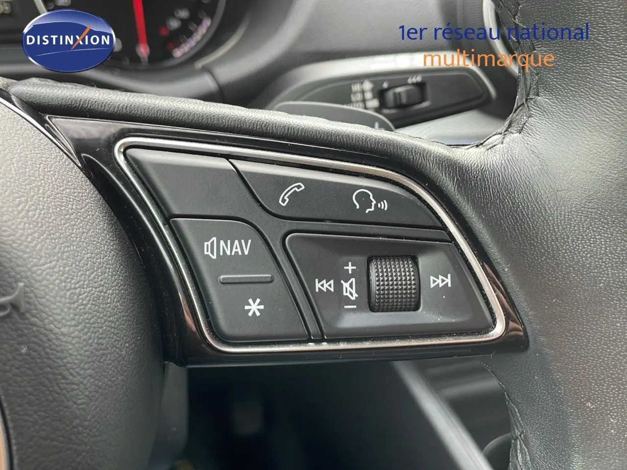 Gros plan sur les commandes multimédia et navigation au volant cuir d'un Audi Q2 noir mito metal 2023.