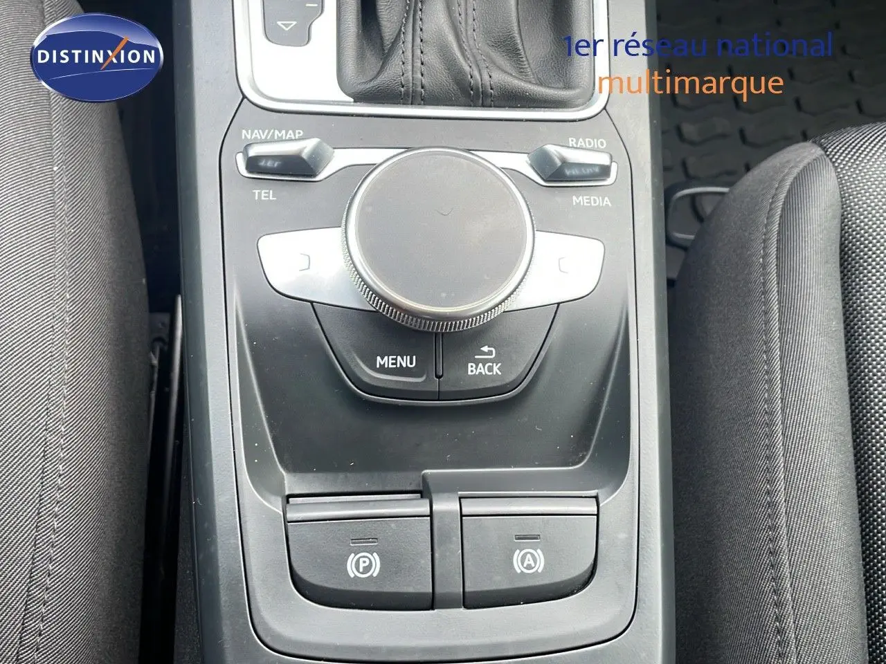 Vue rapprochée de la console centrale noire de l'Audi Q2 35 TFSI S-Line avec commandes multimédia et frein électrique.