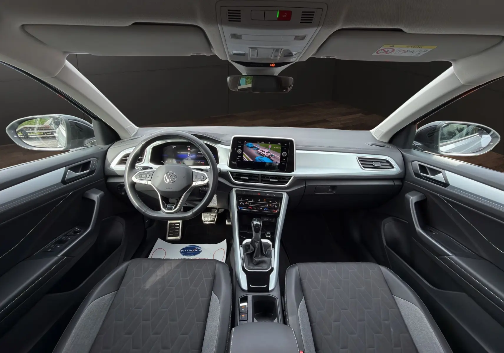 Vue intérieure avant du Volkswagen T-Roc 2025, tableau de bord noir avec écran tactile et volant multifonction cuir.