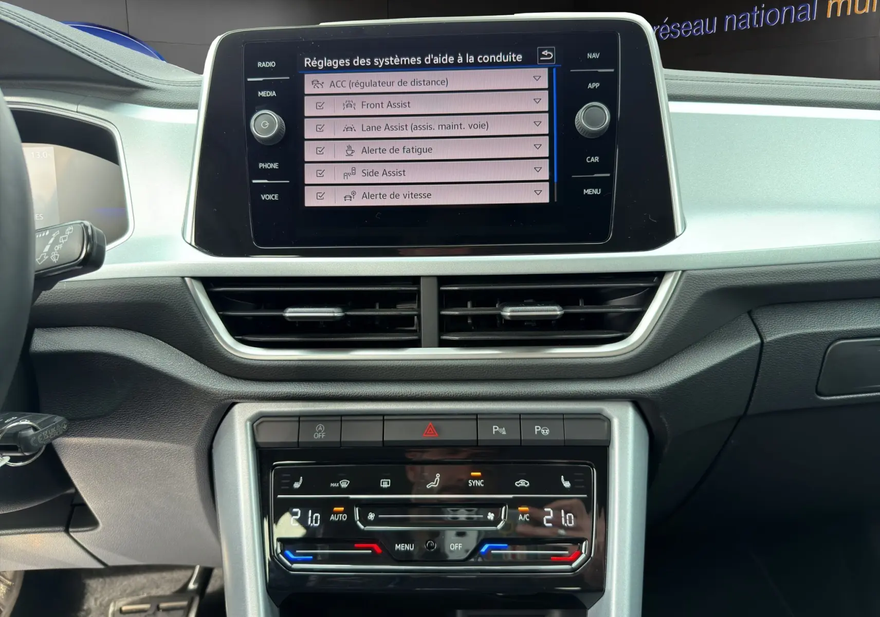 Vue rapprochée du tableau de bord du Volkswagen T-Roc 2025, écran tactile affichant les aides à la conduite.