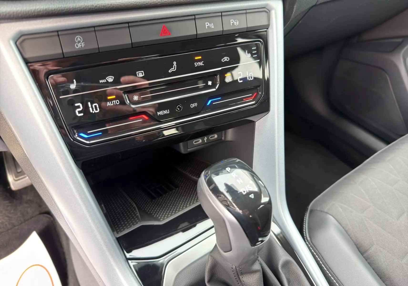 Gros plan sur la console centrale du Volkswagen T-Roc 2025, avec commandes climatisation digitale et levier de vitesse automatique.