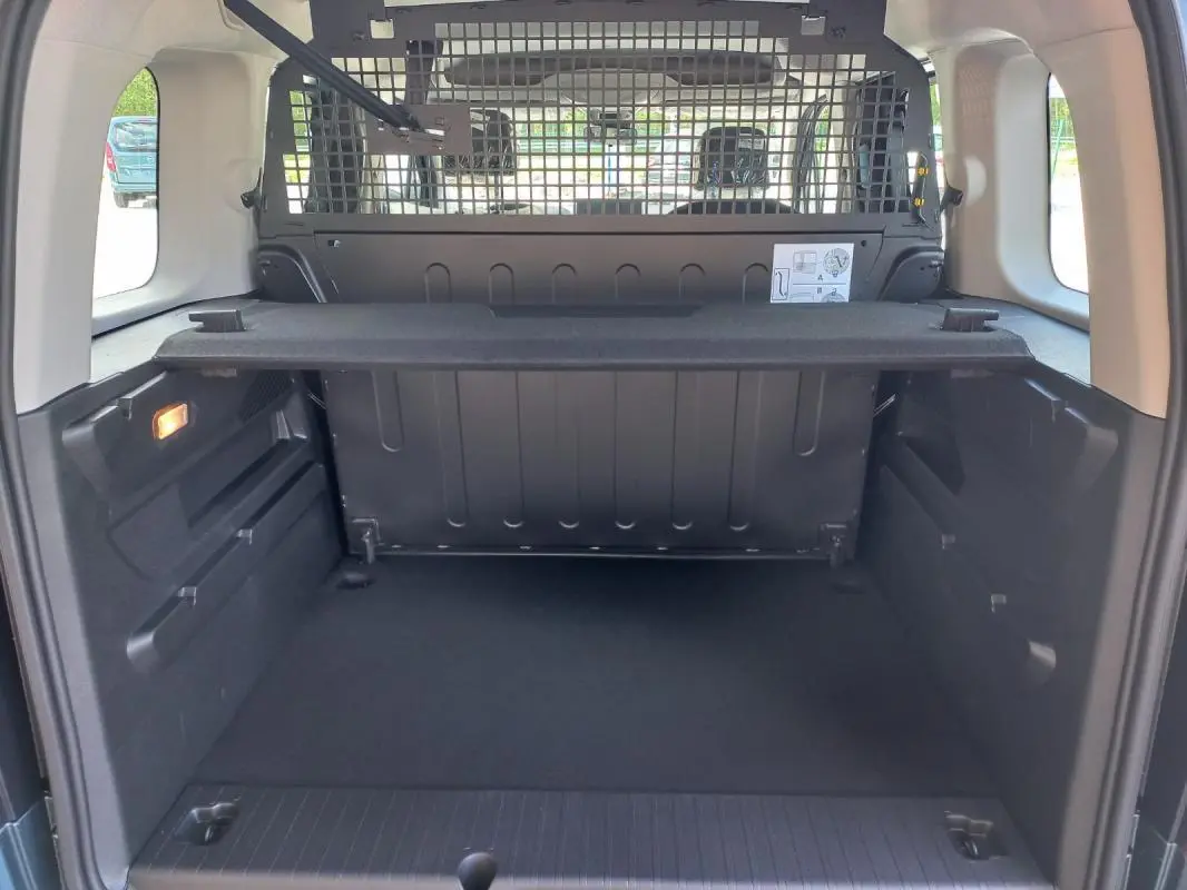 Vue intérieure du coffre arrière d'un Opel Combo Life M 2025, avec séparation grillagée et tablette de rangement noire.