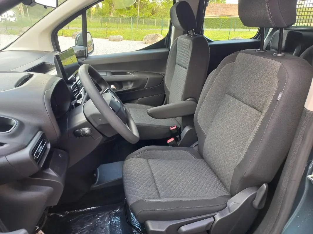 Vue intérieure côté conducteur de l'Opel Combo Life bleu 2025, montrant les sièges tissu gris et le tableau de bord moderne.