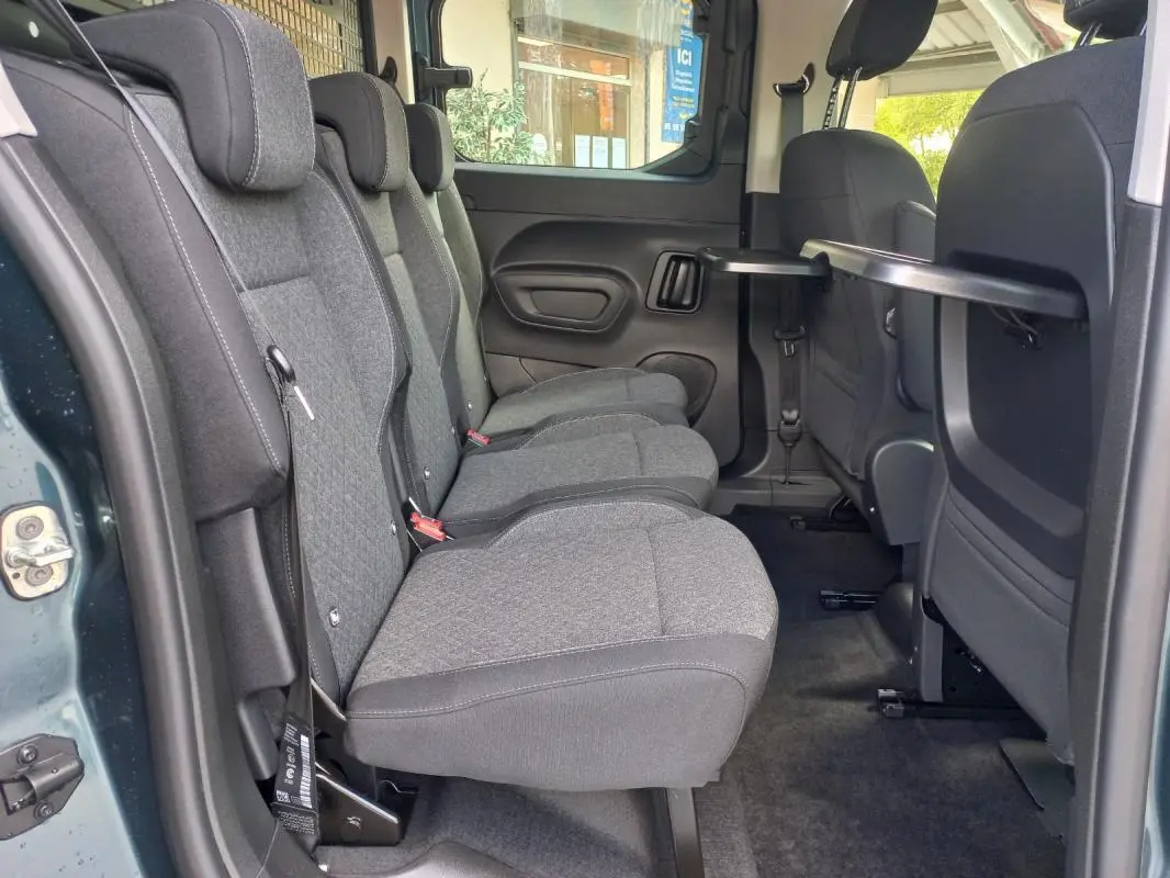 Vue intérieure côté gauche des sièges arrière gris du fourgon Opel Combo Life M 2025, avec tablette rabattable sur le dossier avant.
