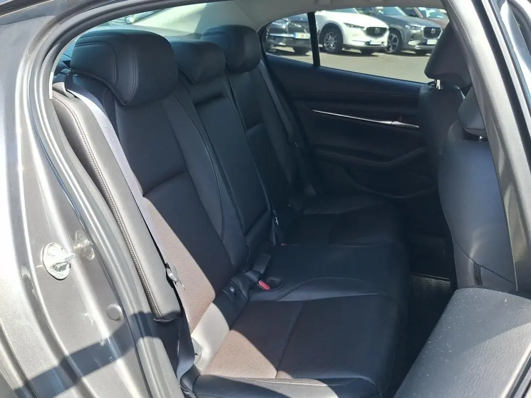 Vue intérieure montrant les sièges arrière en cuir noir d'une Mazda3 gris 2020, porte arrière ouverte côté gauche.