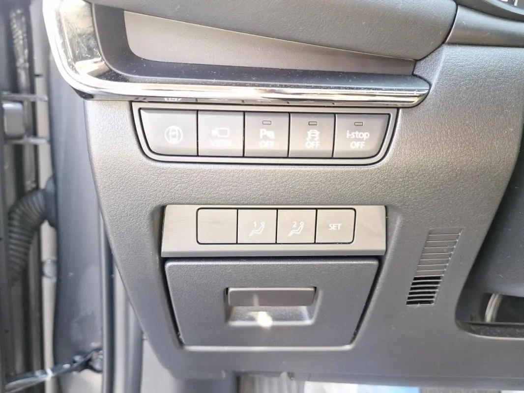 Gros plan sur les commandes de réglages et assistances situées à gauche du volant dans l'habitacle gris du Mazda3 2020.