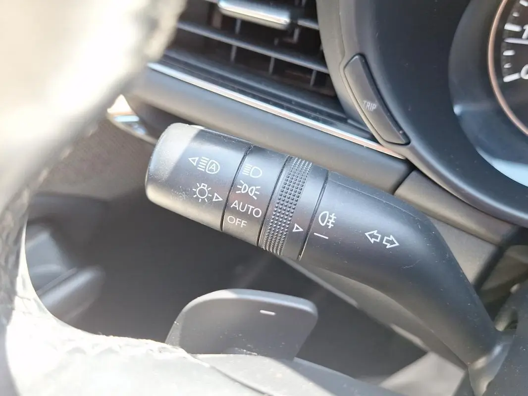 Gros plan sur la commande des phares et clignotants côté gauche du volant de la Mazda3 gris 2020.