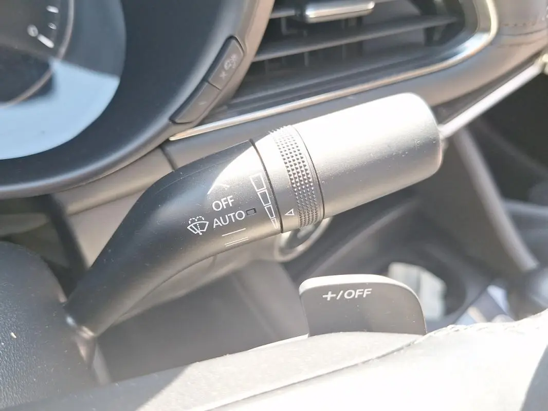 Gros plan sur la manette de commande des essuie-glaces à gauche du volant cuir dans l’habitacle gris de la Mazda3 2020.