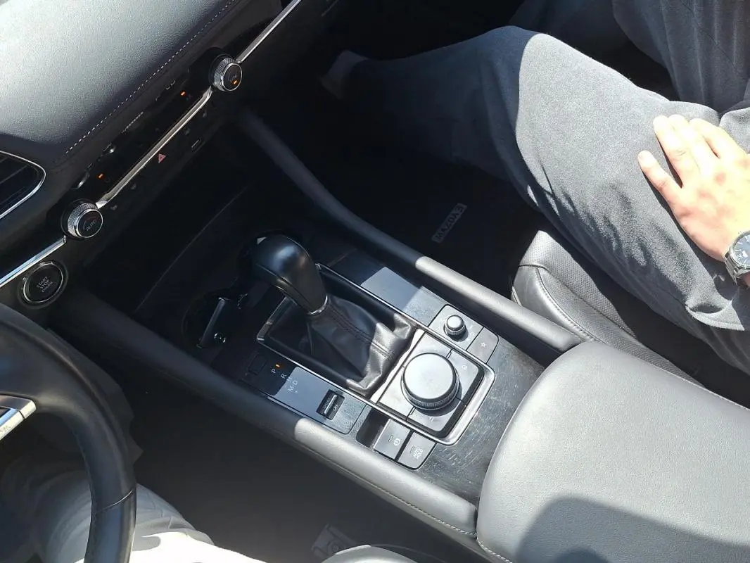 Vue rapprochée de la console centrale noire de la Mazda3 2020 avec levier de vitesse automatique et commandes multifonctions.