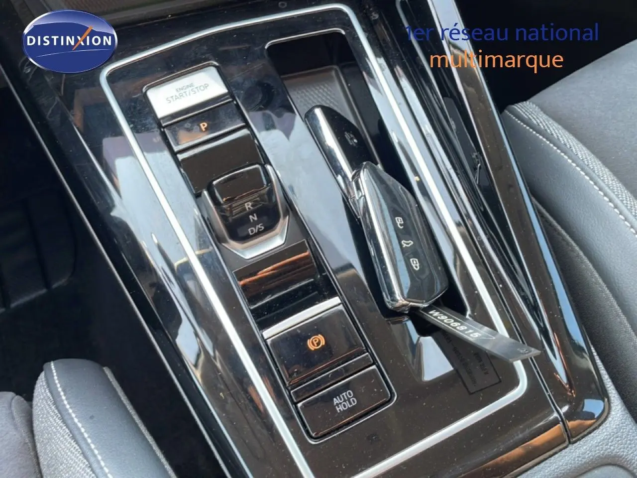 Gros plan sur la console centrale noire brillante de la Volkswagen Golf SW VIII 2024 avec clé de contact posée.