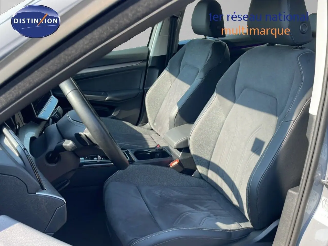 Vue intérieure côté conducteur de la Volkswagen Golf SW VIII gris lunaire, sièges en tissu et cuir gris avec volant multifonction.