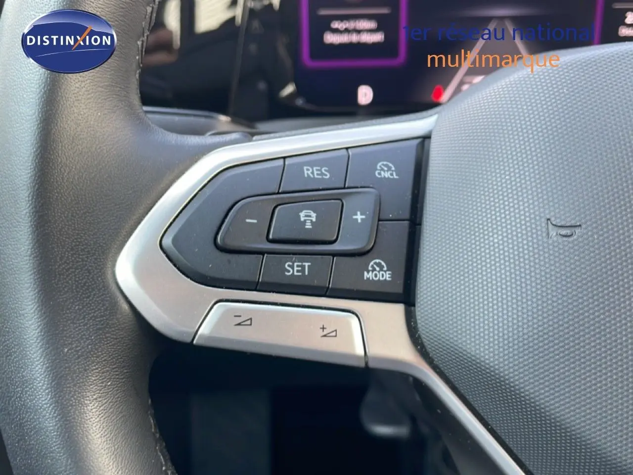 Gros plan sur les commandes au volant à gauche de la Volkswagen Golf SW VIII gris lunaire, avec régulateur de vitesse adaptatif.