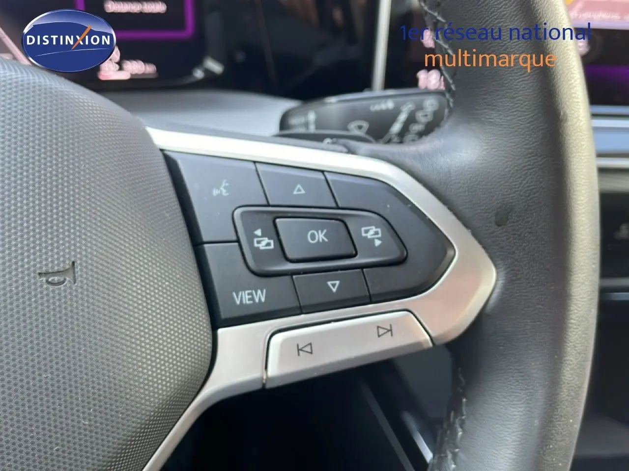 Gros plan sur les commandes gauche du volant en cuir noir de la Volkswagen Golf SW gris lunaire 2024.