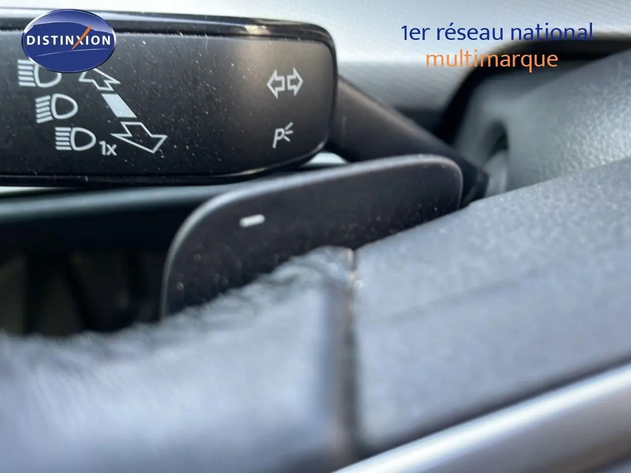 Gros plan sur la commande de clignotants et volant en cuir gris dans l'habitacle d'une Volkswagen Golf SW 2024 gris lunaire.