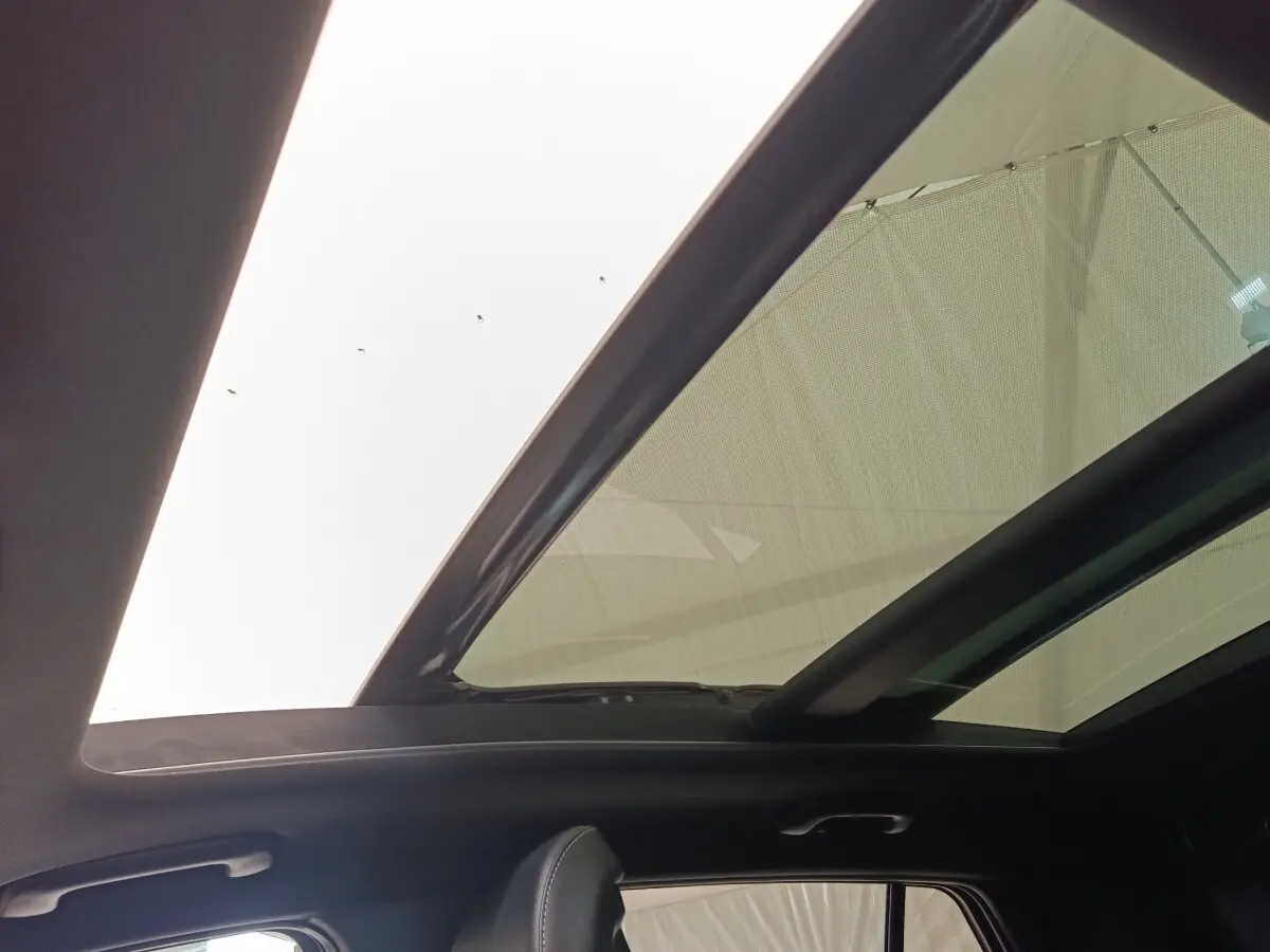 Toit ouvrant panoramique en verre du Kia Sportage gris clair, vue intérieure vers le ciel depuis l'arrière.