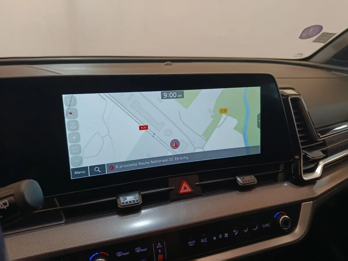 Intérieur du Kia Sportage 2022, vue sur l'écran tactile central affichant la navigation, tableau de bord moderne noir.