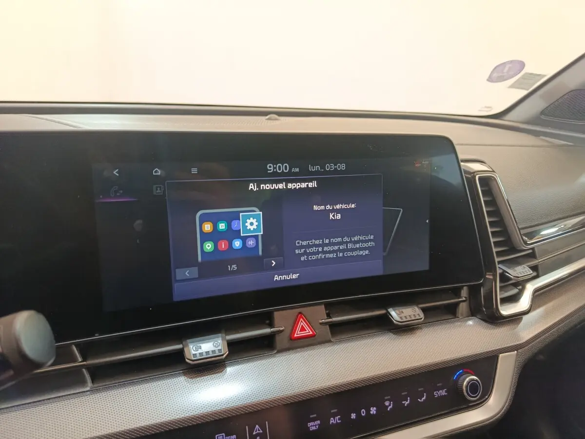 Vue intérieure du tableau de bord du Kia Sportage gris clair 2022, avec écran tactile central allumé affichant le Bluetooth.