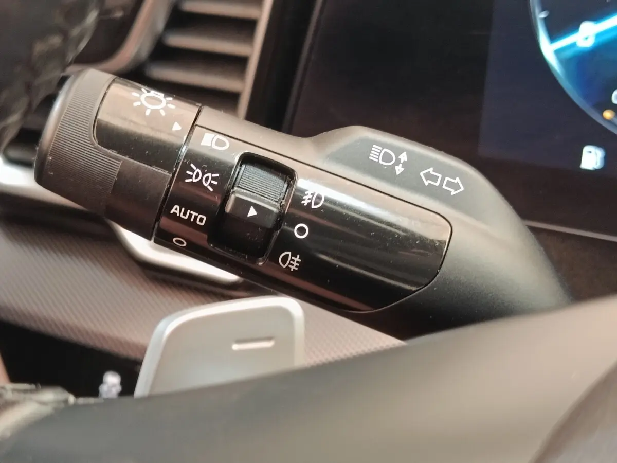 Gros plan sur la commande des feux et clignotants du volant d’un KIA Sportage gris clair 2022, intérieur moderne.
