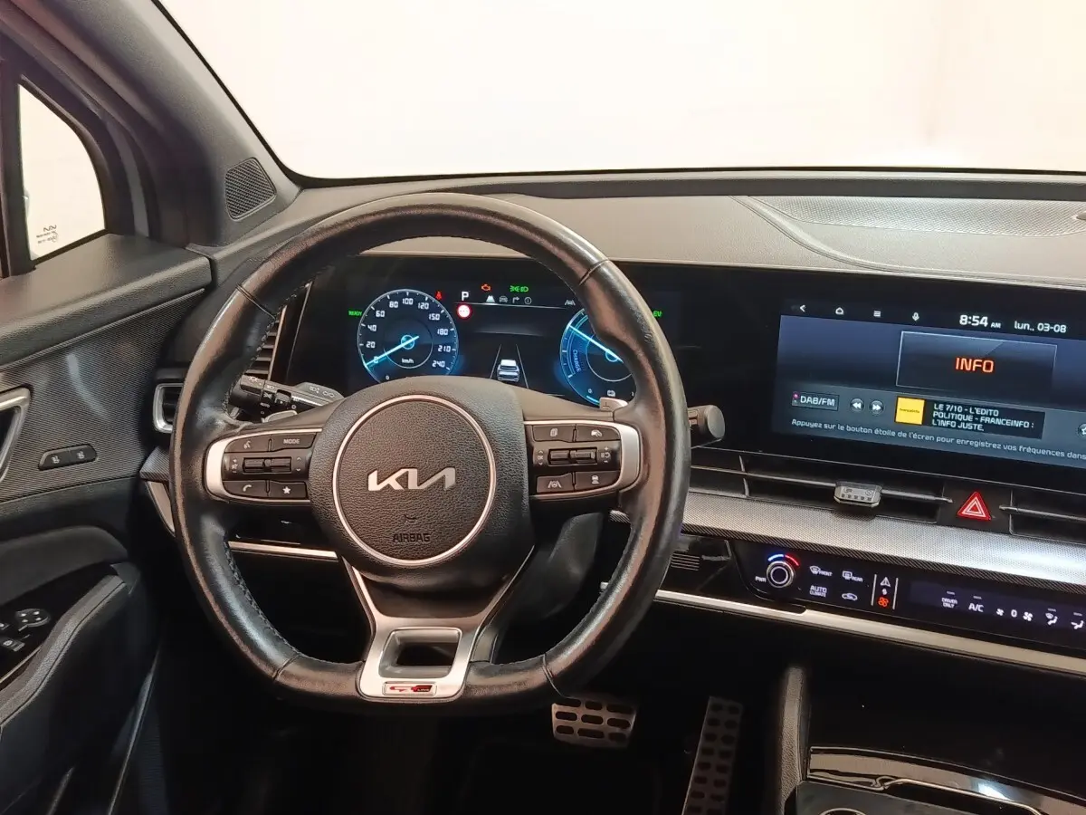 Intérieur du Kia Sportage 2022 vu du poste de conduite, volant cuir GT-Line et tableau de bord numérique lumineux.