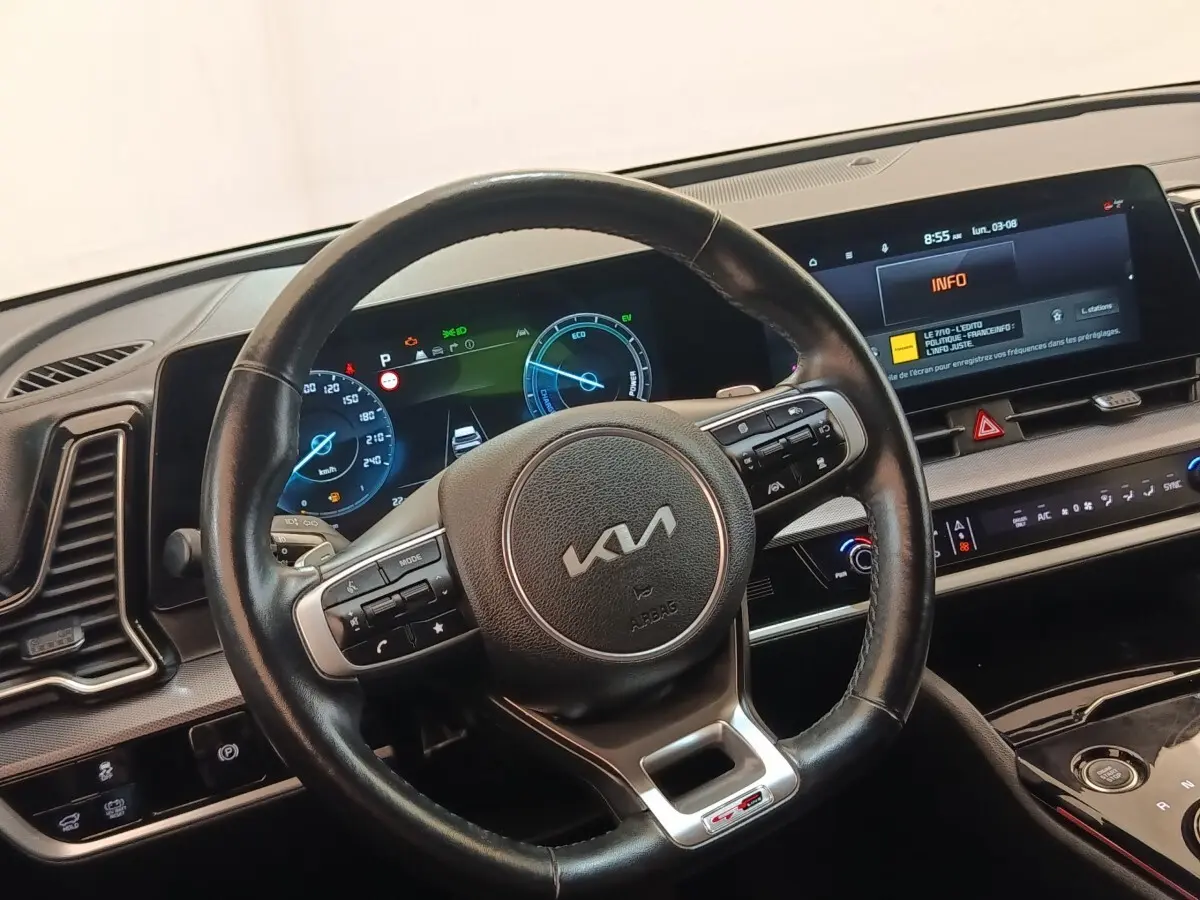 Vue intérieure centrée sur le volant cuir KIA GT-Line avec tableau de bord digital et écran tactile 12,3 pouces.