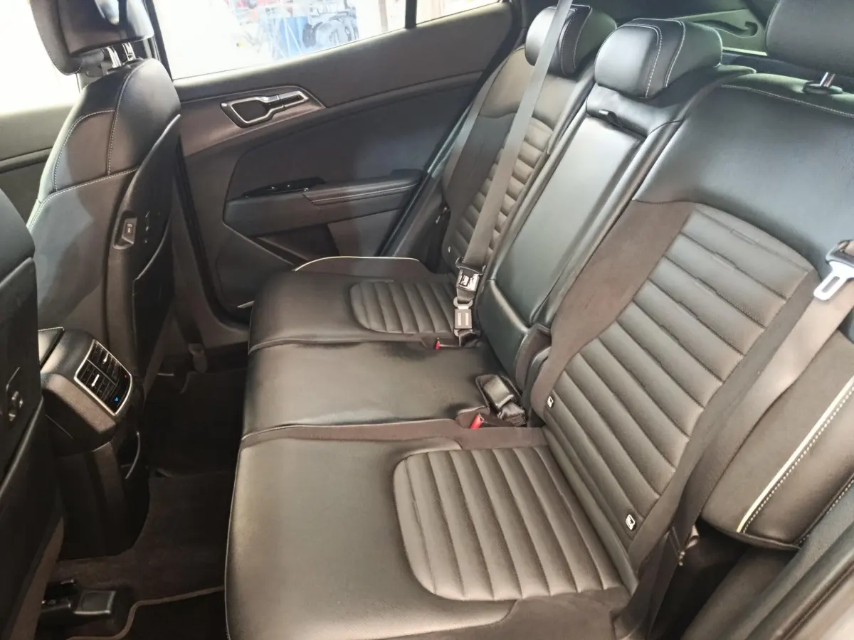 Vue latérale intérieure sur la banquette arrière en cuir noir du Kia Sportage 2022 avec ceintures de sécurité visibles.