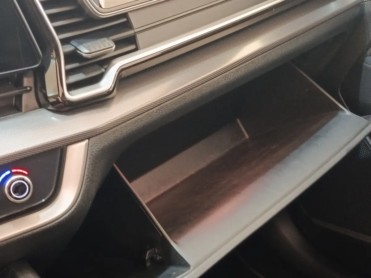 Gros plan sur la boîte à gants ouverte et le tableau de bord gris clair du Kia Sportage 2022 côté passager.
