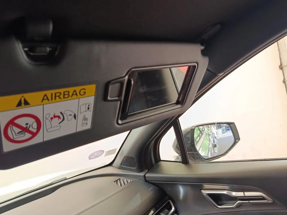 Intérieur côté passager du Kia Sportage gris clair 2022, avec miroir pare-soleil ouvert et rétroviseur extérieur visible.