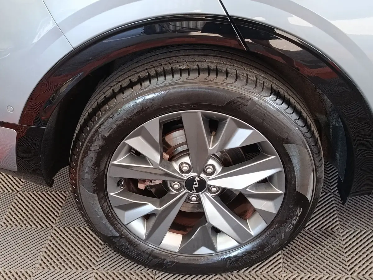 Gros plan sur la roue avant droite du KIA Sportage gris clair, avec jante alliage et logo KIA central visible.