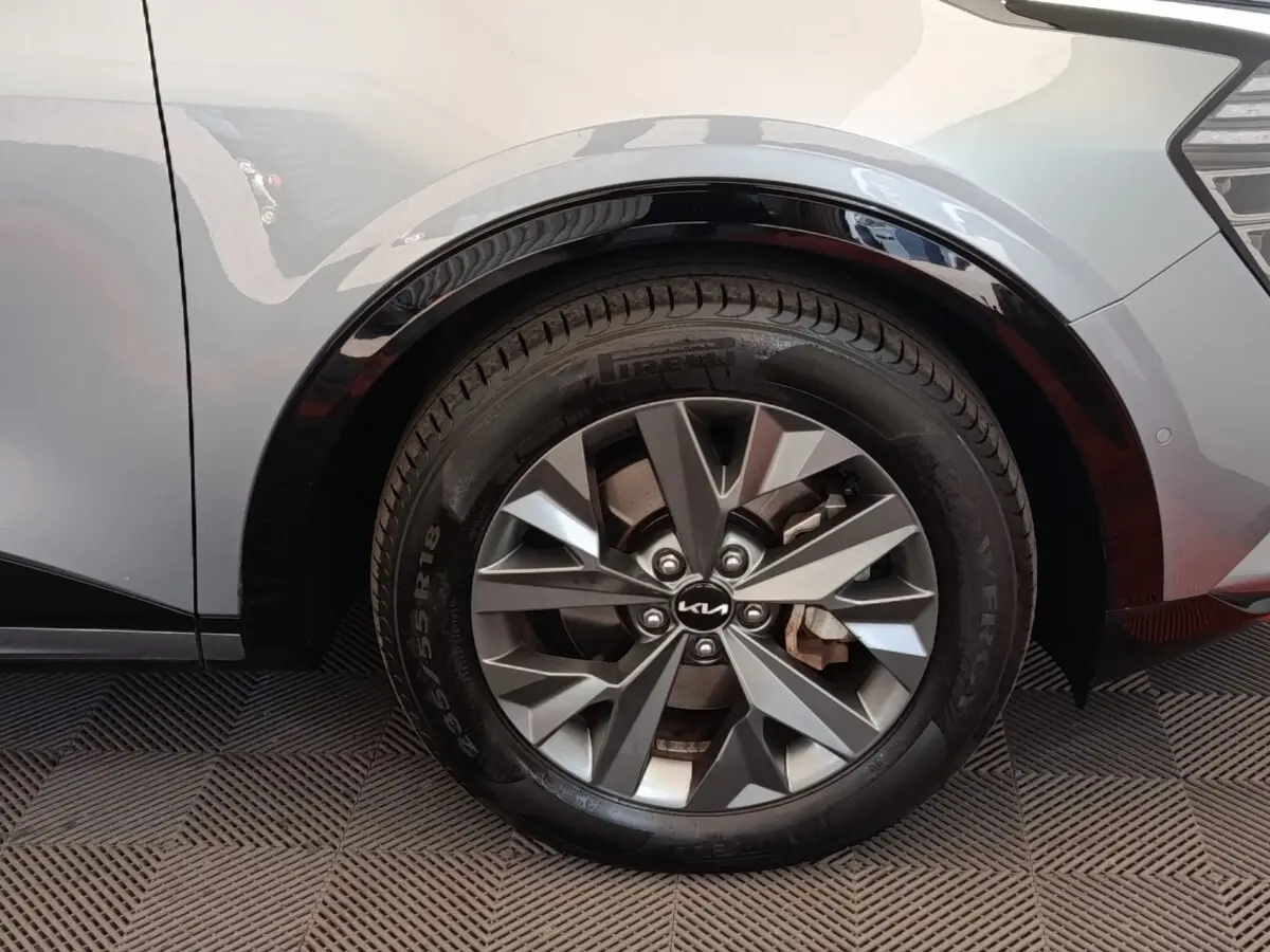 Gros plan sur la roue arrière droite gris clair du Kia Sportage 2022 avec jante alliage et logo Kia central.
