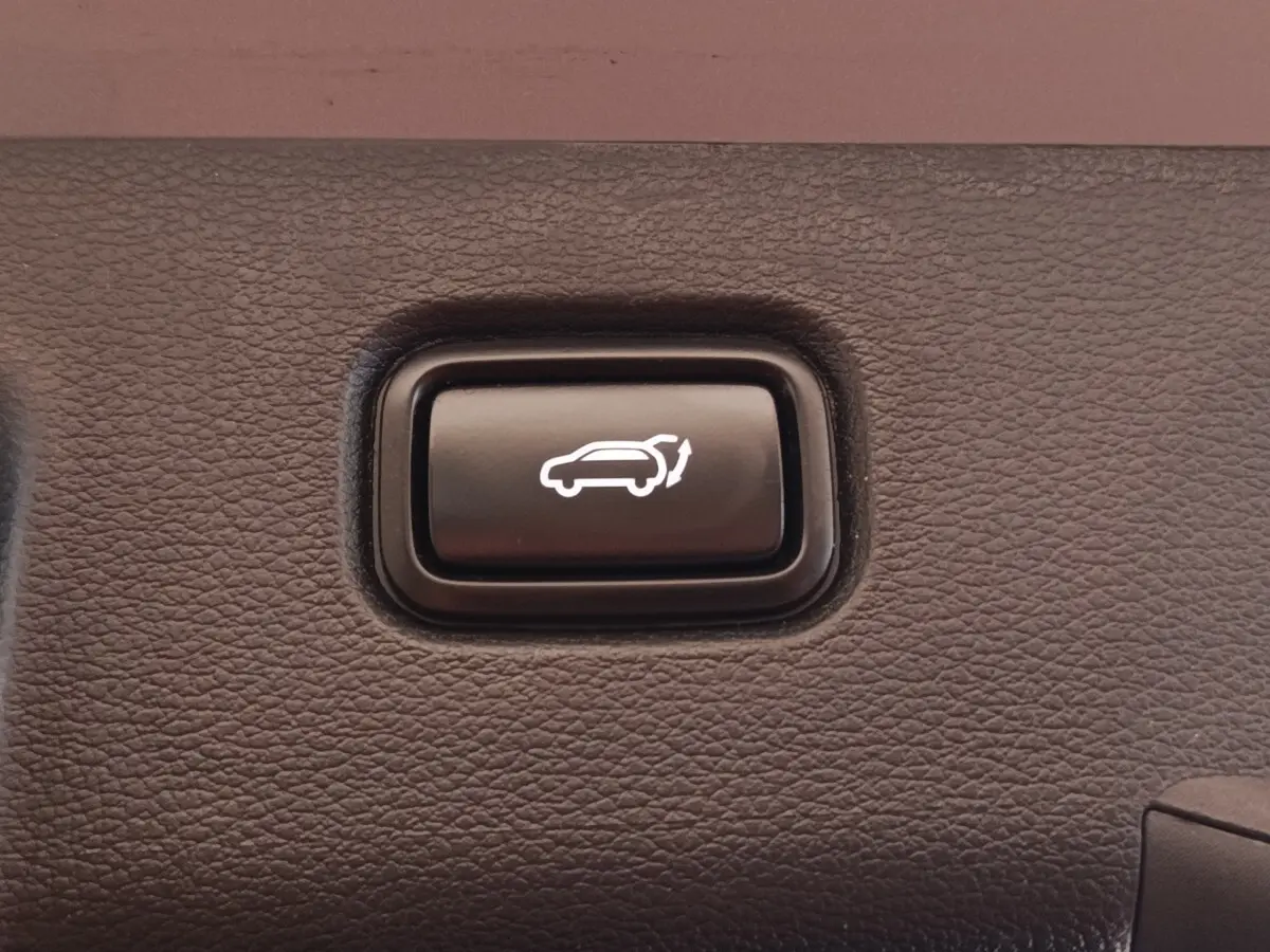 Bouton noir d'ouverture électrique du coffre sur panneau intérieur texturé du Kia Sportage gris clair 2022.