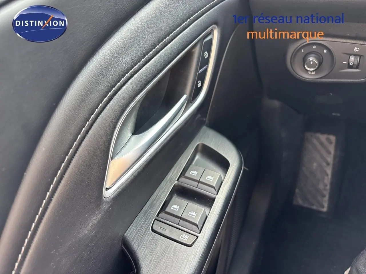 Gros plan sur la commande des vitres côté conducteur en finition noire, avec poignée argentée du MG ZS 2025 Pebble Black.