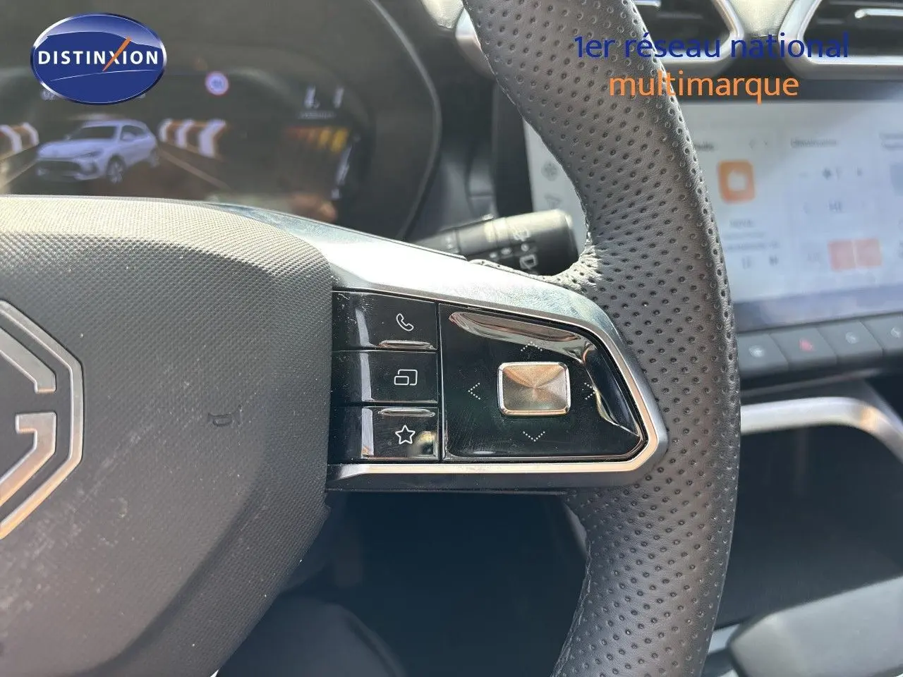 Gros plan sur le volant en cuir perforé noir du MG ZS 1.5L Hybrid+ 197ch Luxury, avec commandes intégrées et tableau de bord numérique.