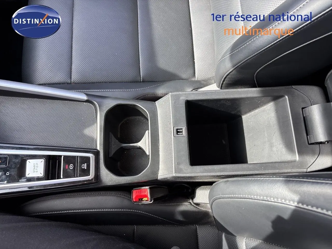 Vue plongeante sur la console centrale noire du MG MOTOR ZS 1.5L HYBRID+ 197CH LUXURY avec porte-gobelets et rangement ouvert.